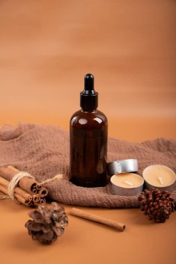 Temel yağ şişesi ve taze tarçın, kahverengi havlu, kahverengi havlu ve kahverengi ahşap arka planda kurutulmuş portakal yaprağı, yakın plan, seçici odak