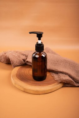 Bir şişe kozmetik ürünü ve bej arka planda boş kağıt.