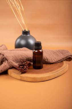 Spa konsepti. Temel yağ şişesi ve kahverengi arka planda kuru kahverengi havlu..