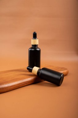 Siyah arka planda kahverengi petrolcü ve pipetli gerekli yağ şişesi. Spa ve vücut bakım ürünleri.