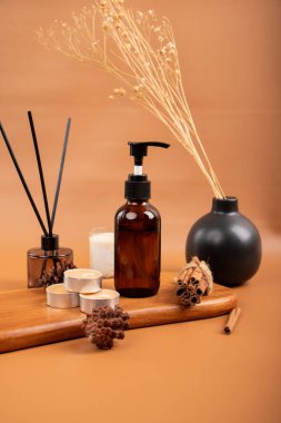 Bir şişe parfüm, kuru çiçek ve bej arka planda kurutulmuş portakal.