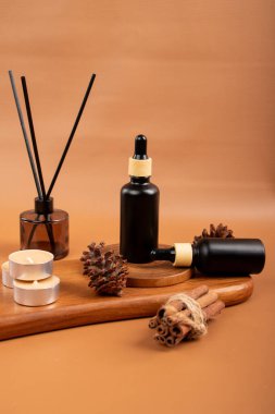 Doğal kozmetik ürünü olan spa konsepti, kahverengi arka planda bir şişe mum ve bir şişe gerekli yağ. Boşluğu kopyala.