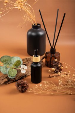 Temel serum ve bej arka planda okaliptüs dalları olan şişeler.