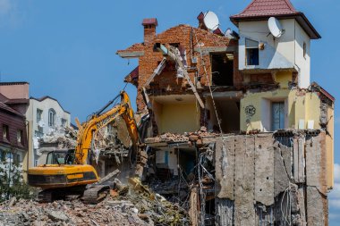 Uzhhorod, Ukrayna - 23 Mayıs 2023: Şehir bölgelerinden birinde eski bir binanın yıkılması üzerinde çalışan kazıcı.