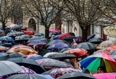 Uzhhorod, Ukrayna - 23 Mart 2025: Şiddetli bir bahar yağmuru sırasında şehir merkezinde şemsiye altında yürüyen bir kalabalık.