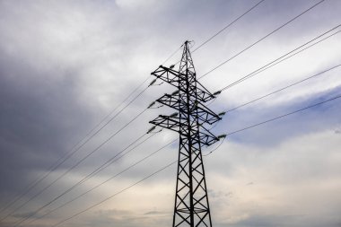 Bulutlu bir gökyüzünün arka planında birçok kabloya sahip bir elektrik istasyonu