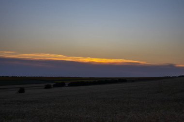 Gün batımı zaten karanlık olan gökyüzünde sarı bir çizgi oluşturur..