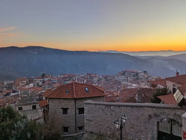 Yunanistan 'ın Arachova dağ kasabasına bakan sıcak altın renkleriyle nefes kesici bir gün batımı manzarası.