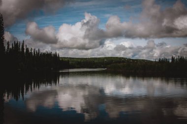 Alaska gölünün dinginliğini hisset dramatik, bulutlu bir gökyüzünü yansıt. Doğa, dinginlik ve macera teması için mükemmel. Bu görüntü Alaska 'nın el değmemiş güzelliklerini yakalıyor..