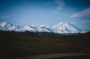 Alaska 'nın karlarla kaplı dağlarının dingin güzelliğine dalın. Bu panoramik çekim, berrak mavi gökyüzünün altındaki görkemli tepeleri yakalar. Seyahat, doğa ve macera temaları için mükemmeldir..