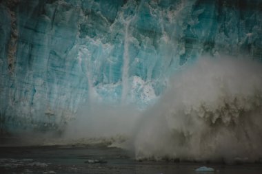 Doğanın ham gücüne tanık olun. Büyük bir buz kütlesi Alaska buzulundan kırılarak patlayıcı bir sıçrama yaratıyor. Çevre ve seyahat projelerinde dinamik ve dramatik görsel içerik için mükemmel.