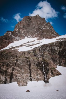 Yükselen bir dağı ve çağlayan şelalesi olan Alaska buzulunun muhteşem manzarası. Bu çarpıcı fotoğraf, Kuzey Kutbu bölgesinin ham güzelliğini ve sakin doğasını yakalıyor..