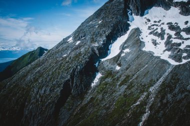 Alaska 'nın engebeli dağ manzarasının ham güzelliğini bir helikopterden çek. Bu hava çekimi, doğa ve macera içeriği için mükemmel dramatik kayalık zirveler, kar yamaçları ve yemyeşil alanları vurgular..