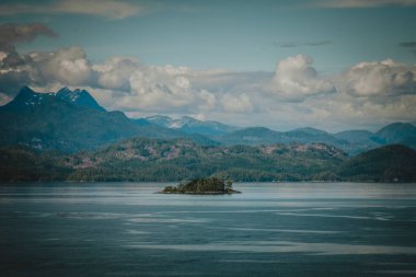 İzole edilmiş bir ada engin Alaska sularında, görkemli dağlar ve dramatik bulutlar tarafından çerçevelenmiş, uzak doğal güzellikleri ve sakin manzaraları gösteren projeler için ideal..