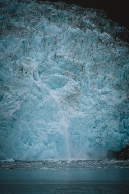 Karmaşık buz dokularıyla aşağıdaki soğuk sulara dökülen Alaska buzulunun çarpıcı görüntüsü kutup çöllerindeki doğanın saf güzelliğini ve gücünü yakalıyor..