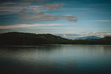 Bu büyüleyici fotoğrafla Alaska 'nın el değmemiş güzelliğini deneyimleyin. Sakin suları, yemyeşil suları ve berrak mavi gökyüzünün altındaki görkemli dağları..