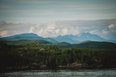 Bu çarpıcı fotoğraf görkemli Alaska sıradağlarını, yemyeşil ormanları, engebeli zirveleri ve dramatik bulutları yansıtıyor. Doğa ve macera temalı görseller için mükemmel.
