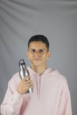 Bir adam karanlık bir arka planda bir şişe su tutuyor..