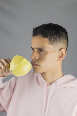 Bir bardak su tutan sıradan giysili genç bir adam.