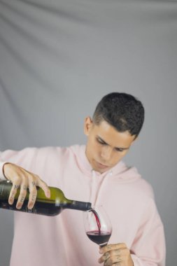 Gri arka planda bir şişe şarabı olan genç bir adam. yüksek kaliteli fotoğraf.