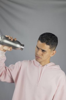 Genç yakışıklı adam şişeden su içiyor.