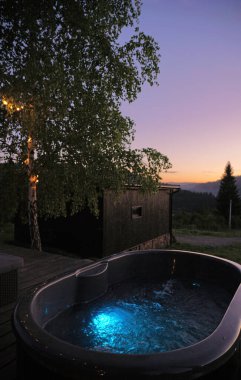 Hot tub behind a wooden cabin in the mountains of Ukraine with copy space clipart