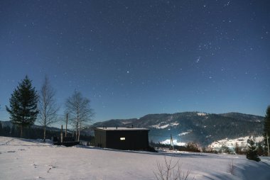 Geceleri panoramik karlı dağ manzaralı ahşap ev.