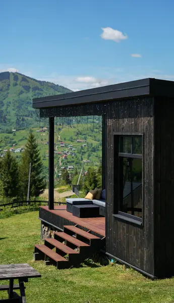 Dağ manzaralı siyah ahşap bir ev.