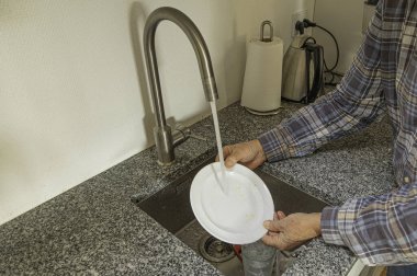 24 Ekim 2024 'te Danimarka' da bir adam mutfak lavabosunda bir tabak duruluyor.