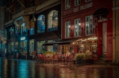 Kopenhag 'da gece sahnesi. 23 Kasım 2024 'te Danimarka' da aydınlık bir restoranın önünde oturan insanlar