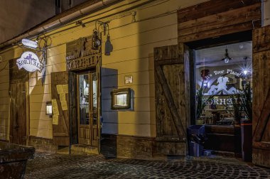 Küçük dar bir arka sokaktaki otantik Macar restoranı, Pecs, Macaristan, 13 Mart 2025, gece aydınlandı.