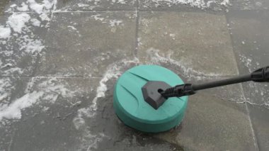 yüksek basınçlı çamaşır makinesi çimento karolarına köpüklü su püskürtüyor çimento ve toprakla kaplanmış.