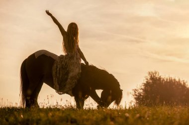 Romantik gün batımı manzarası: Genç bir kadın İzlandalı atıyla sarılıp etkileşime giriyor