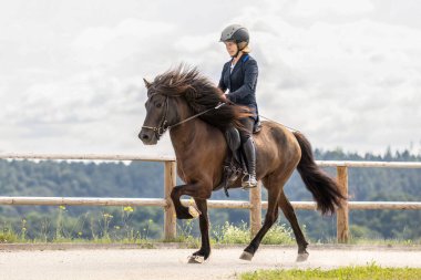 Genç bir kadın, yazın açık havada at binme yarışında dört nala koşuyor.