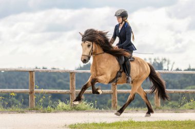 Genç bir kadın, yazın açık havada at binme yarışında dört nala koşuyor.