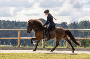 Genç bir kadın, yazın açık havada at binme yarışında dört nala koşuyor.