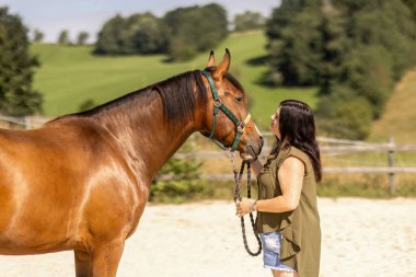 Genç bir kadın dışarıda atla bağ kuruyor. Güven ve şefkat gösteriyor.