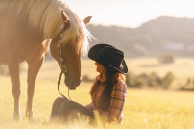 Altın gün batımında Haflinger atı ile farkındalık ve uyum; kadın ve at bağlantısı