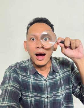 Beyaz arka planda büyüteç tutan Asyalı bir adamın selfie 'si.