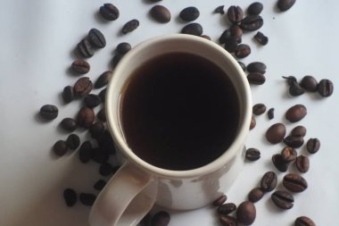 Kahve çekirdeğinin arkasında bir fincan kahve.