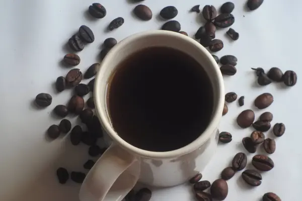 Kahve çekirdeğinin arkasında bir fincan kahve.