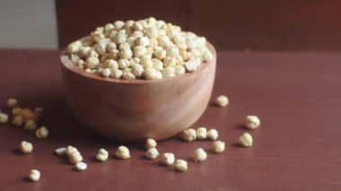 Ahşap tabakta nohut, ahşap masa arkasında.