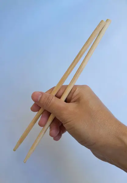 Beyaz arka planda izole edilmiş yemek çubuklarını tutan bir kadın.