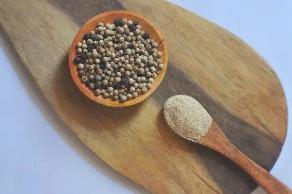 Tahta kaşıkta siyah biber ve beyaz arka planda kaşık
