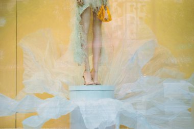 Model's legs on a white pedestal in a showcase window.