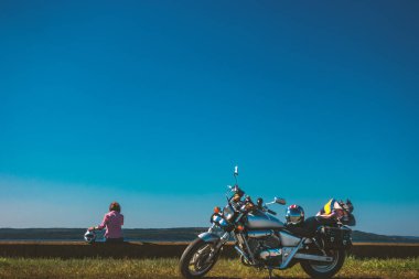 Nehrin kenarında duran motosikletin kaskında bir kadın barajda oturuyor.