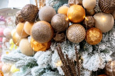 Karla kaplı ağaçta altın Noel topları.