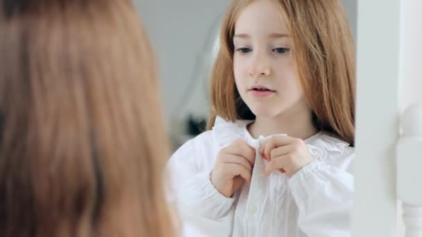 Маленька Мила Дівчинка Застібає Свою Старомодну Білу Піжаму Перед Дзеркалом — стокове відео