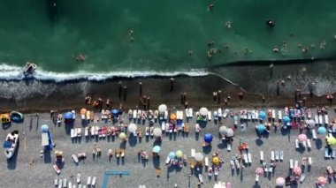 İnsansız hava aracı sahilden yükseliyor. Deniz kenarı, yukarıdan kumsal manzarası.