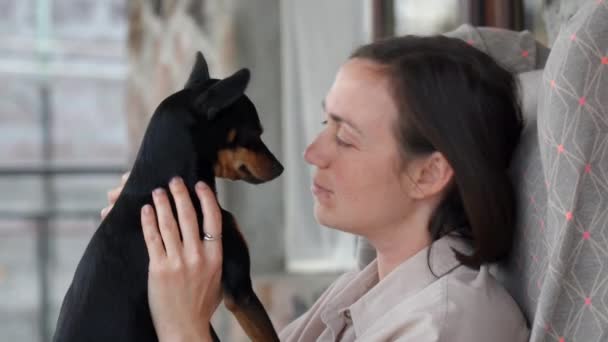 Nuori Nainen Istuu Terassilla Nojatuolissa Hyväilee Hellästi Pientä Koiraansa — kuvapankkivideo